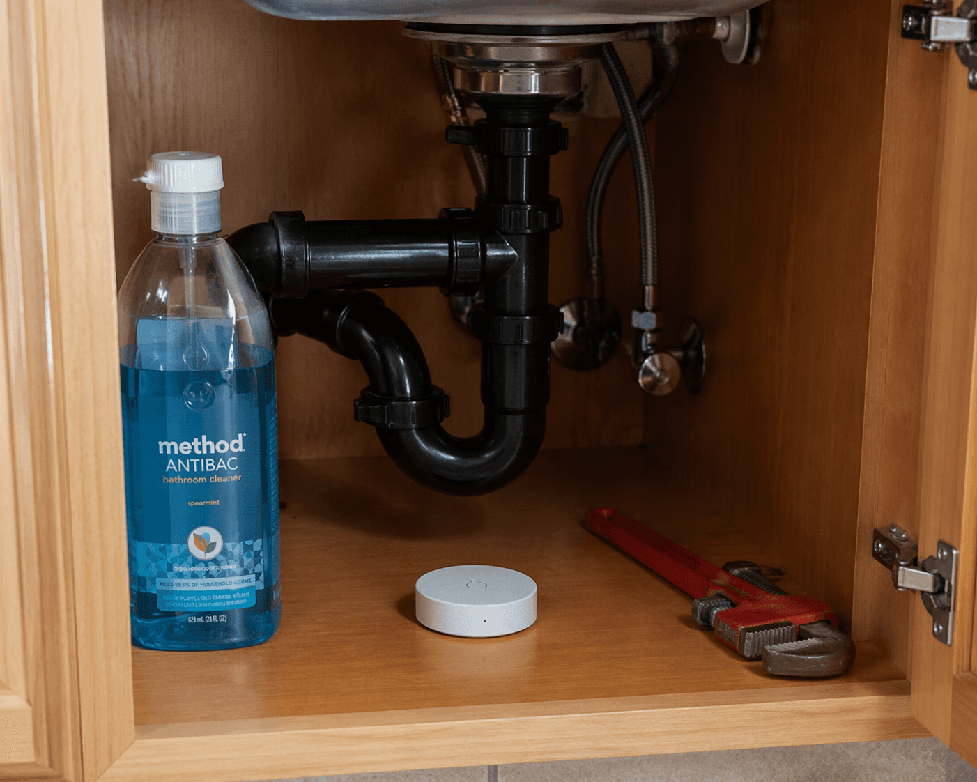 Battery-powered water leak sensor placed under an apartment kitchen sink with no wiring or plumbing modification