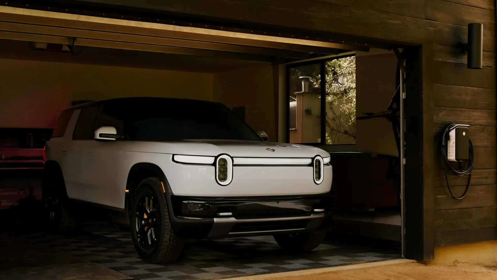 Rivian R2 connected to a home charging station outdoors