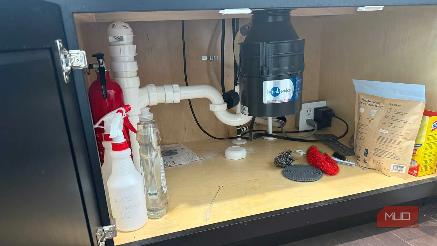 Compact smart water leak detector positioned under a kitchen sink near the drain pipe